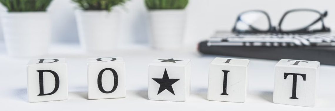 Minimalist desk setup with motivational blocks spelling 'Do It' and small potted plants.